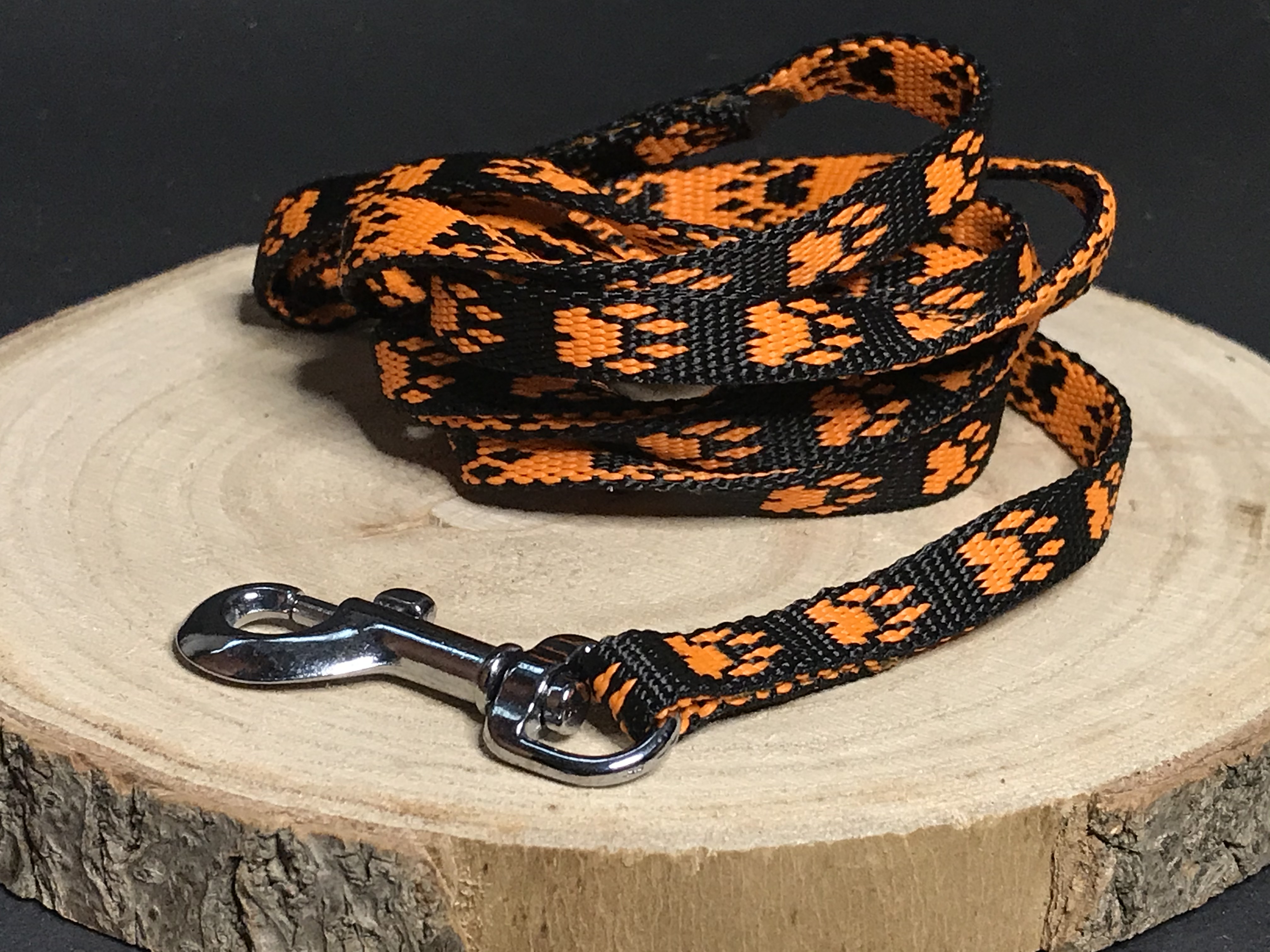 Palkar vodítko z popruhu pre psov 150 cm x 10 mm čierno-oranžová s labkami