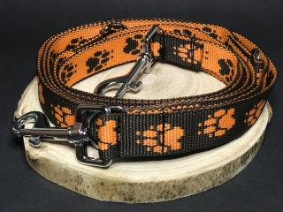 Palkar vodítko prepínacie z popruhu pre psov 250 cm x 25 mm čierno-oranžová s labkami